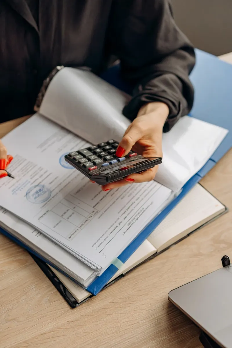 Manos que usan una calculadora sobre documentos en una mesa