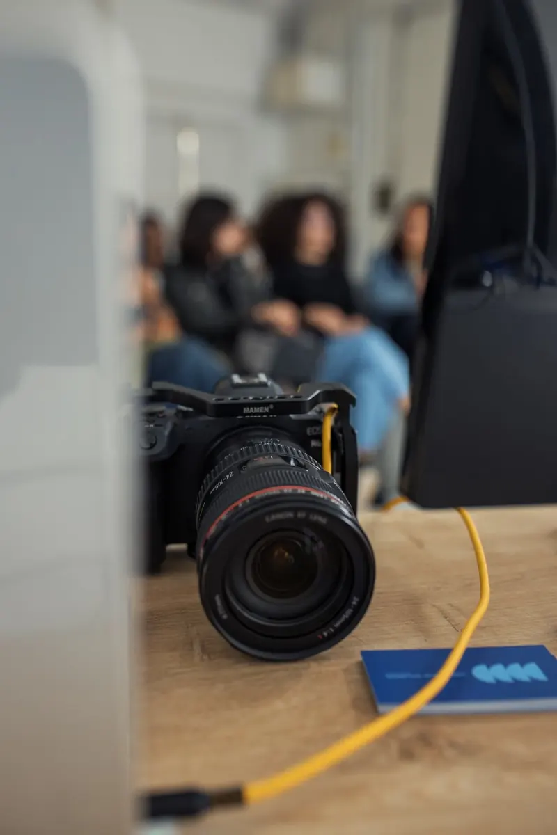 Cámara fotográfica sobre una mesa con personas al fondo