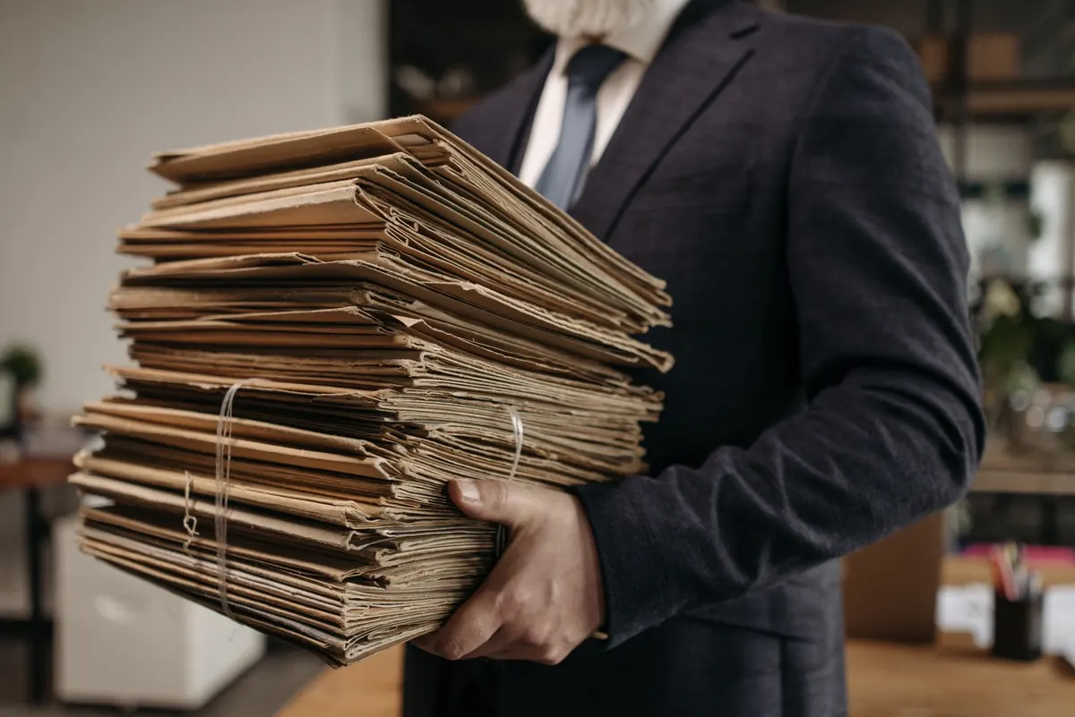 Persona que sostiene una pila grande de carpetas de papel