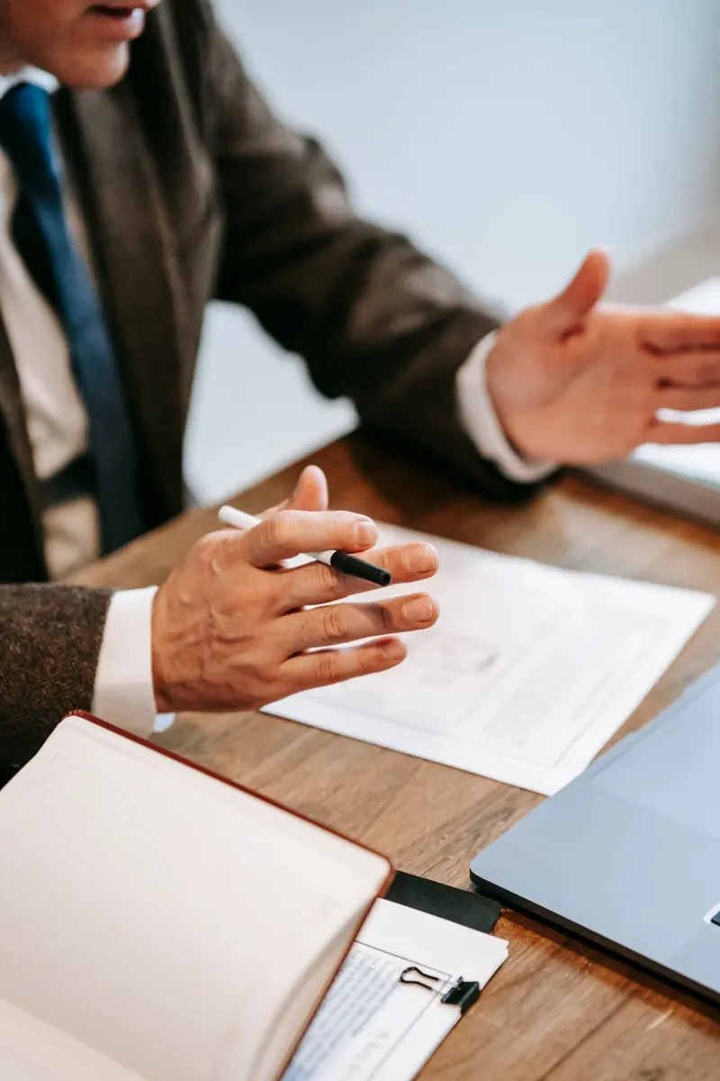 Dos personas conversan sobre documentos en una mesa de madera