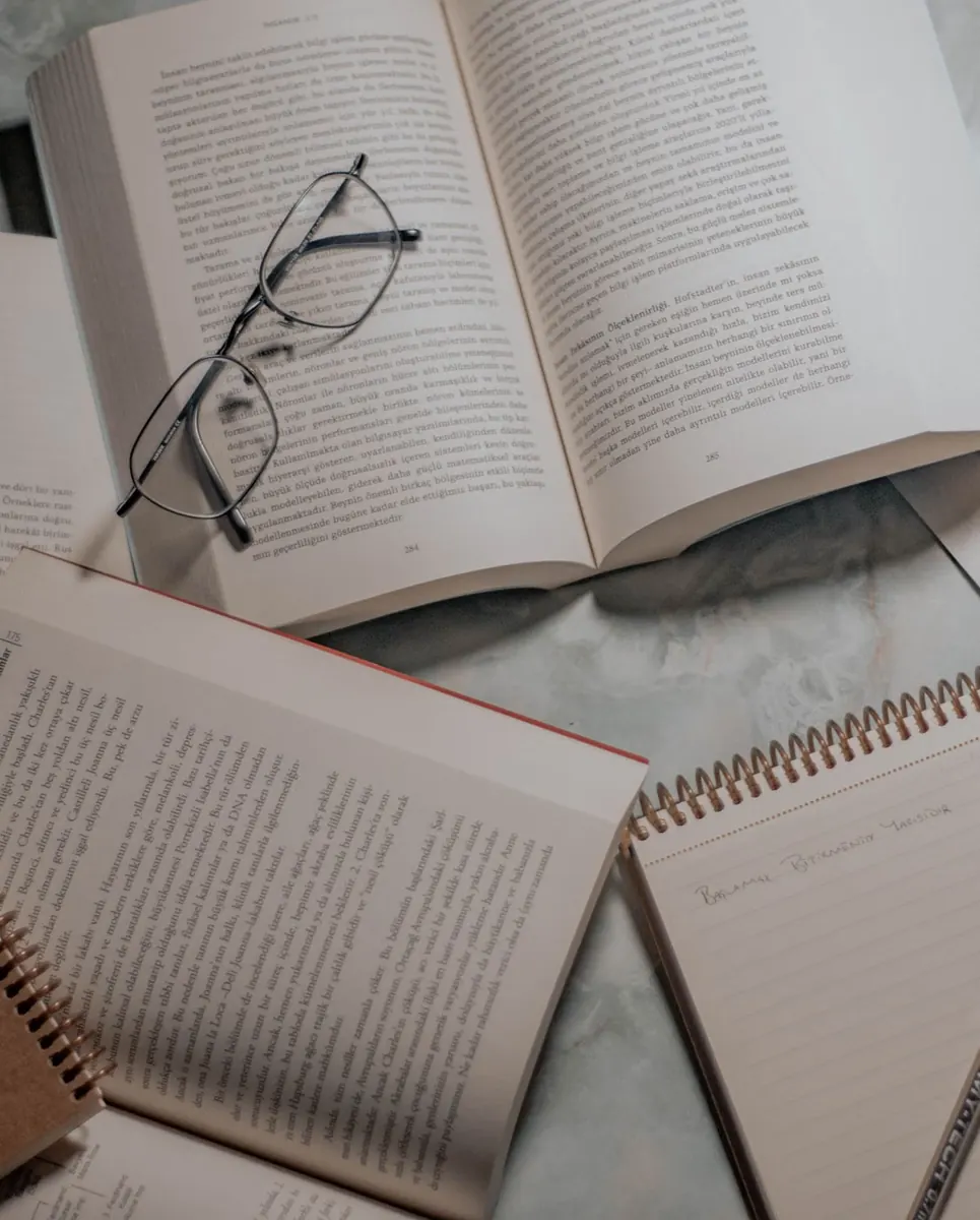 Libros abiertos, gafas y cuaderno vistos desde arriba