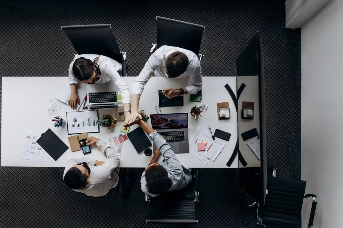 Vista superior de un equipo que trabaja con portátiles y documentos