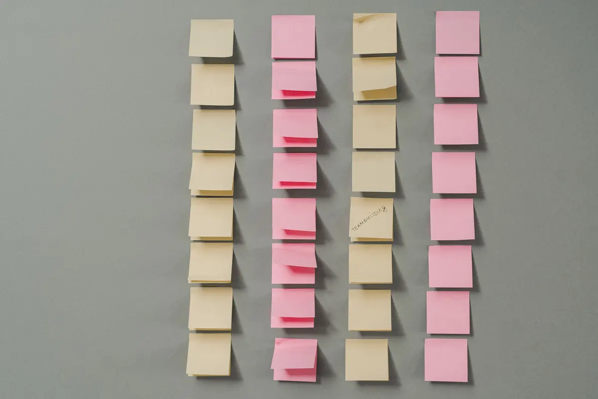 Notas adhesivas rosas y amarillas ordenadas en columnas