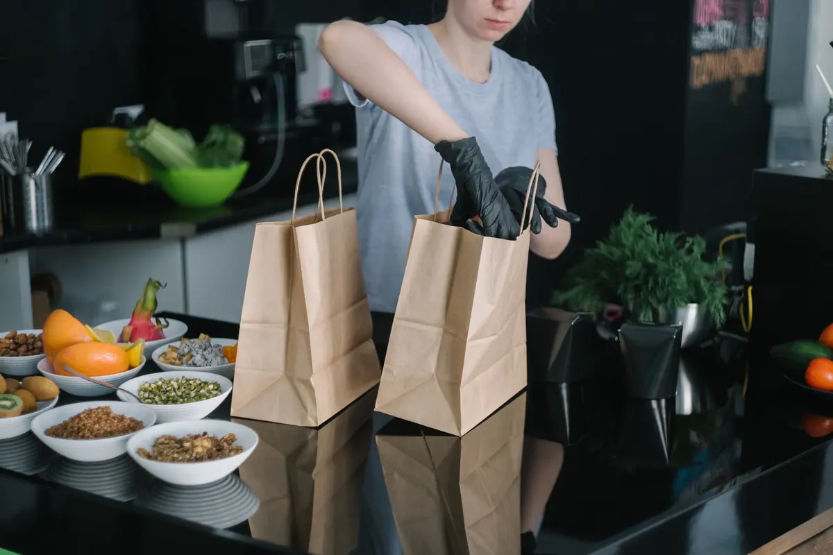 Persona que prepara bolsas de papel con alimentos para llevar