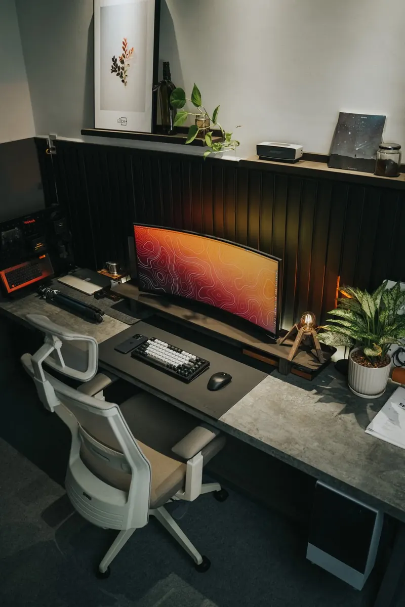 Escritorio con monitor curvo, teclado, plantas y silla de oficina