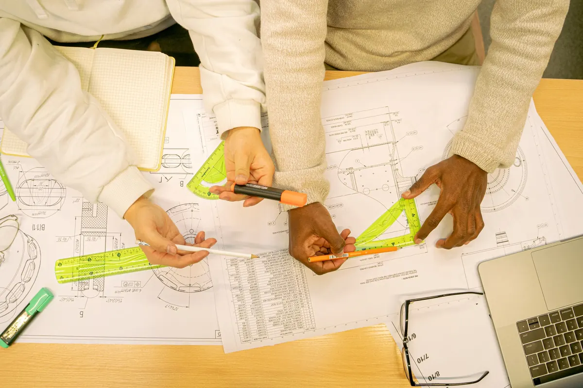 Manos que trabajan sobre planos con reglas y lápices