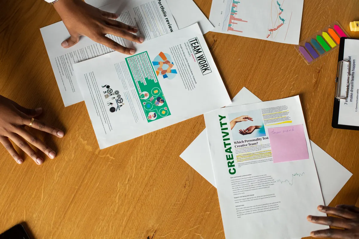 Manos alrededor de documentos con gráficos, textos y notas de colores