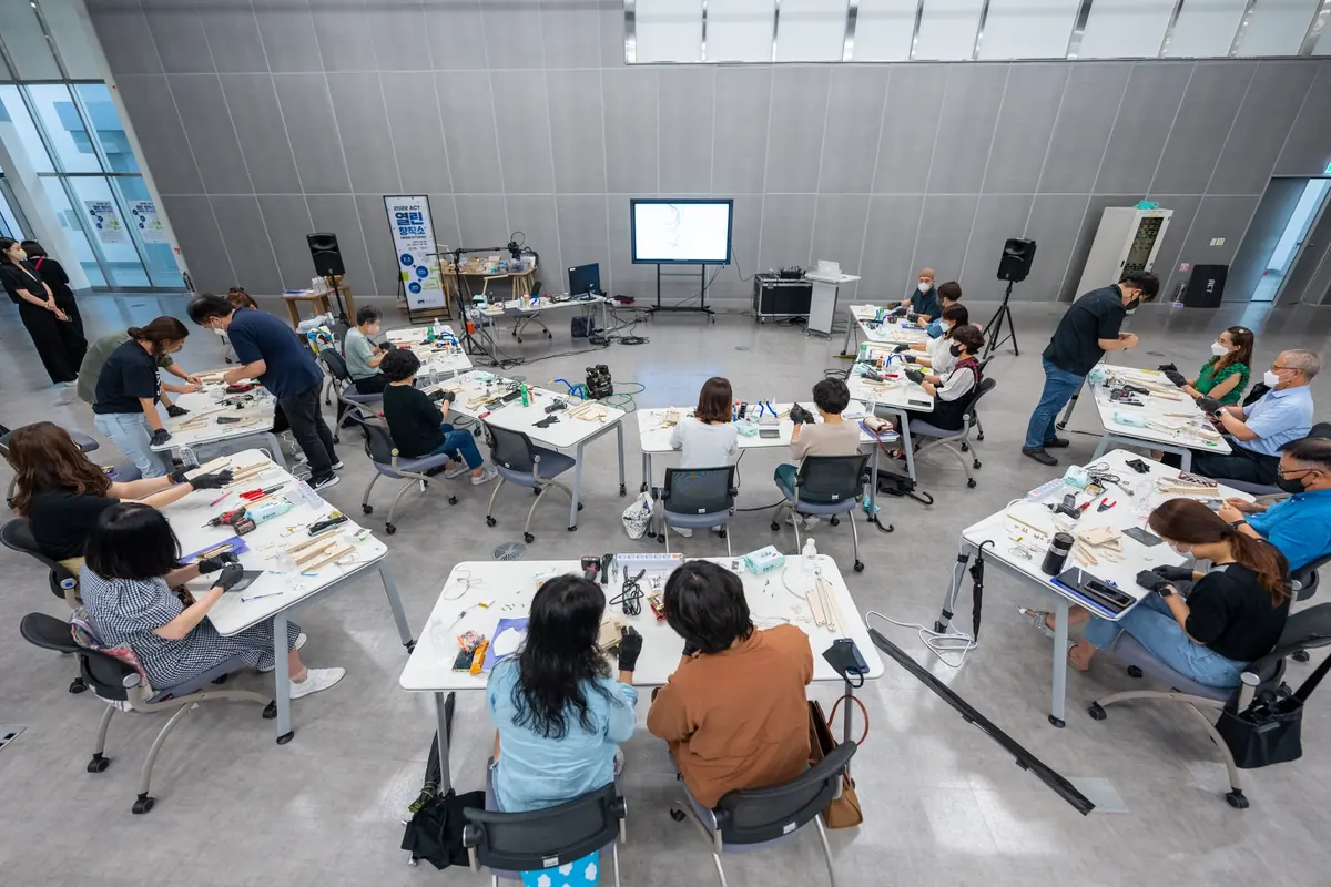Vista de un taller con personas trabajando en mesas y equipos